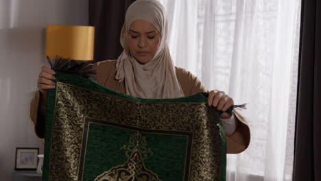 Muslimische-Frau-Mit-Hijab-Zu-Hause-Legt-Gebetsteppich-Auf-Etage-1